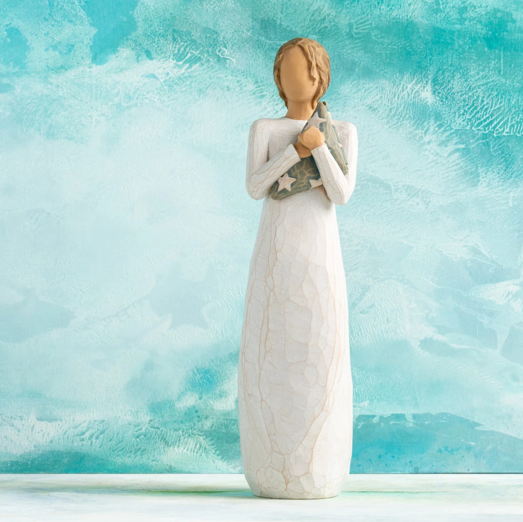 Willow Tree Hero, 9.5”h hand-painted standing resin figure in cream dress holding folded American flag in her arms,  in front of aqua painting