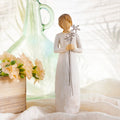 Willow Tree Grateful, 9”h hand-painted standing resin figure in cream dress, holding three wire flowers with long stems, on table with florals