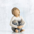 Little girl figurine sitting with legs crossed - faceless - wearing white shirt and blue jeans