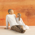 Willow Tree Father and Daughter, 5”h hand-painted resin figure of seated man dressed in neutral colors, legs outstretched, daughter in cream dress by his side, in front of sienna painting