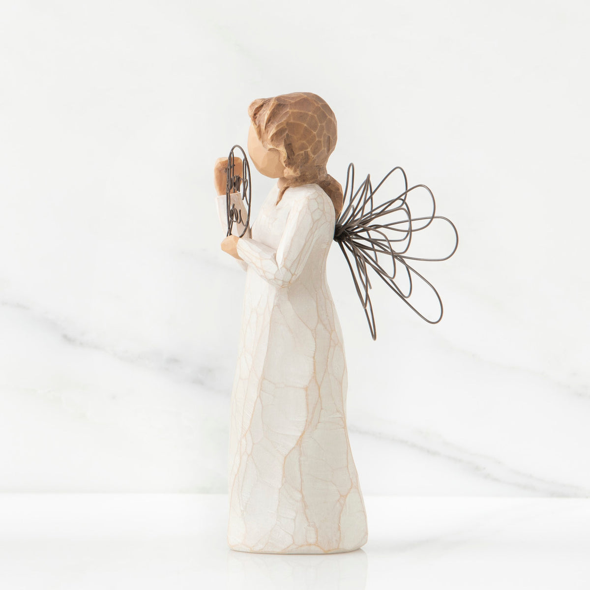 Right side view of angel with tied back brown hair, holding up a circular wire sign that says "thank you"