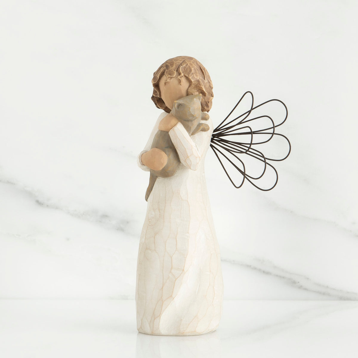 Small brunette angel figurine in white dress holding golden cat