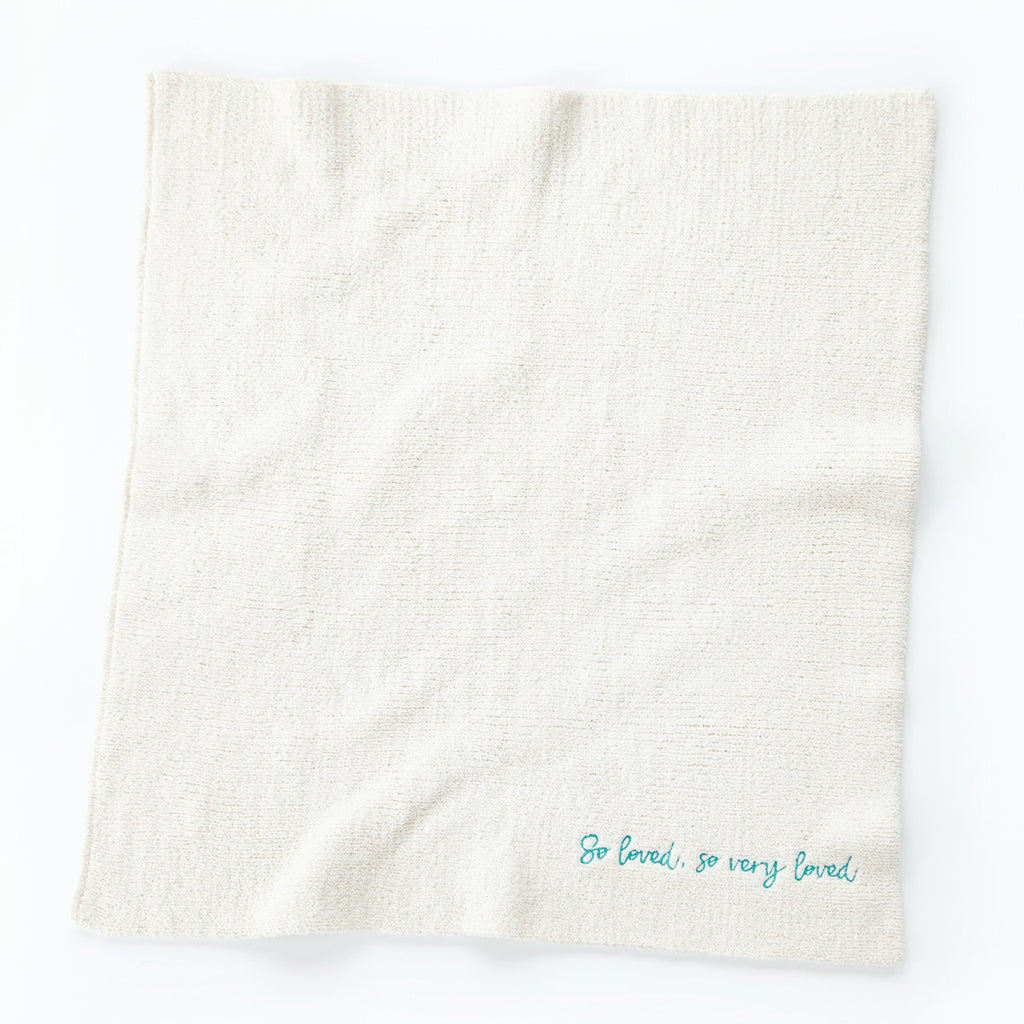 Overview of white towel with 'so loved, so very loved' in light blue in the right corner