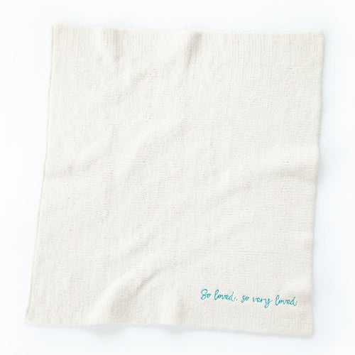 Overview of white towel with 'so loved, so very loved' in light blue in the right corner