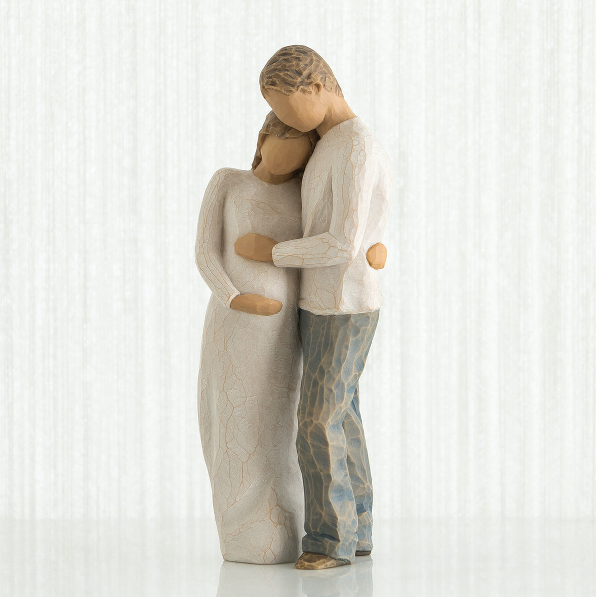 Man and woman figurines dressed in white holding the woman's stomach - white background