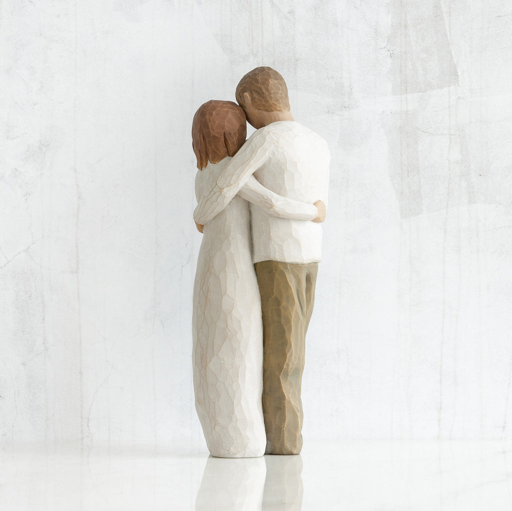 Man and woman figurines - back view - hugging another