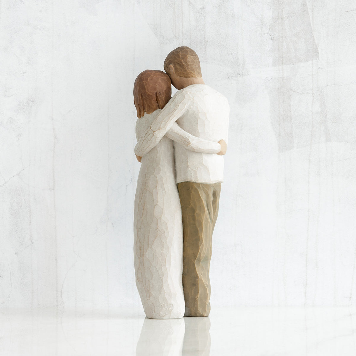 Man and woman figurines - back view - hugging another