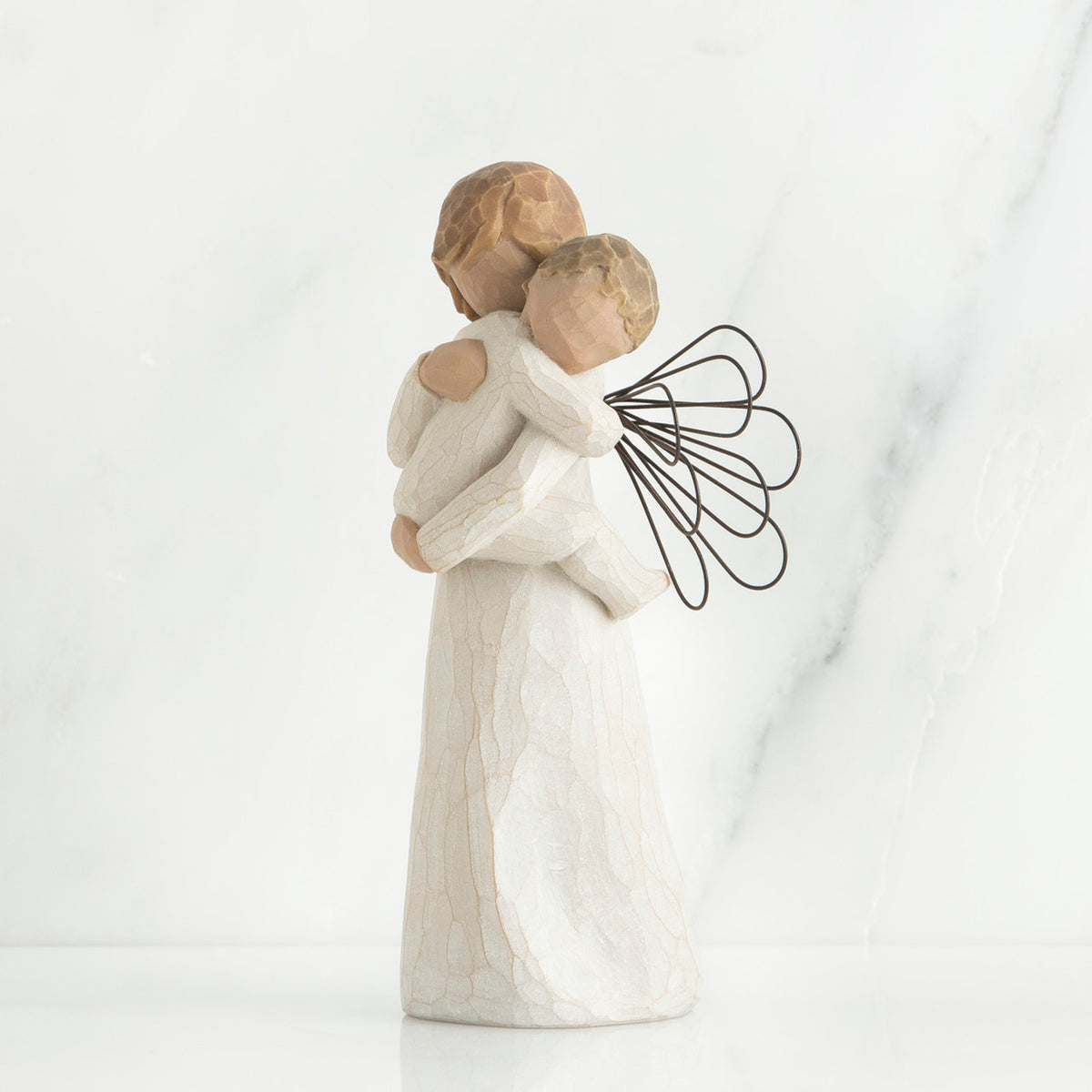 Angel figurine with black wire wings  in white holding baby in her arms