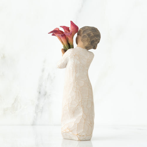 Back view of little girl with short brown hair holding a cluster of red calla lilies