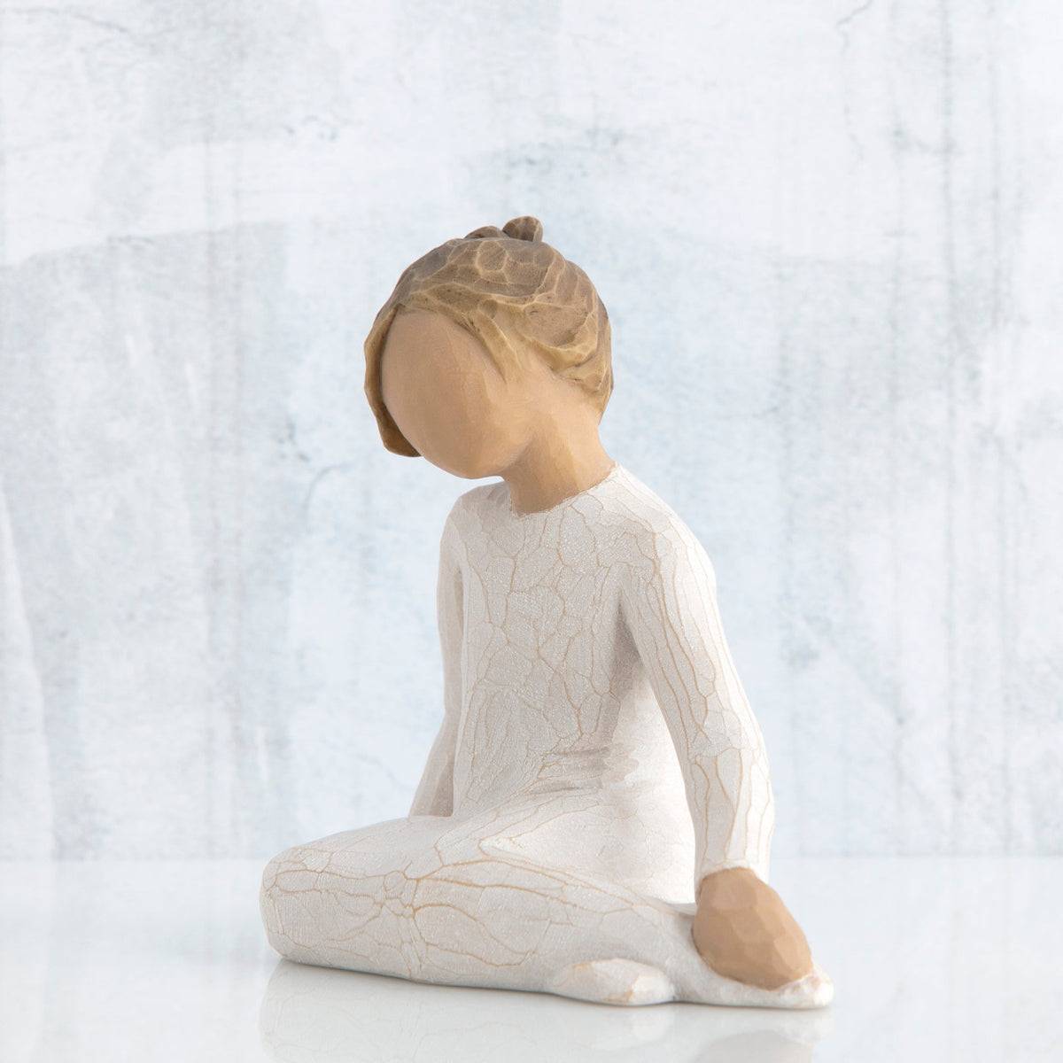 Small young brunette girl figurine in white siting down looking to the side