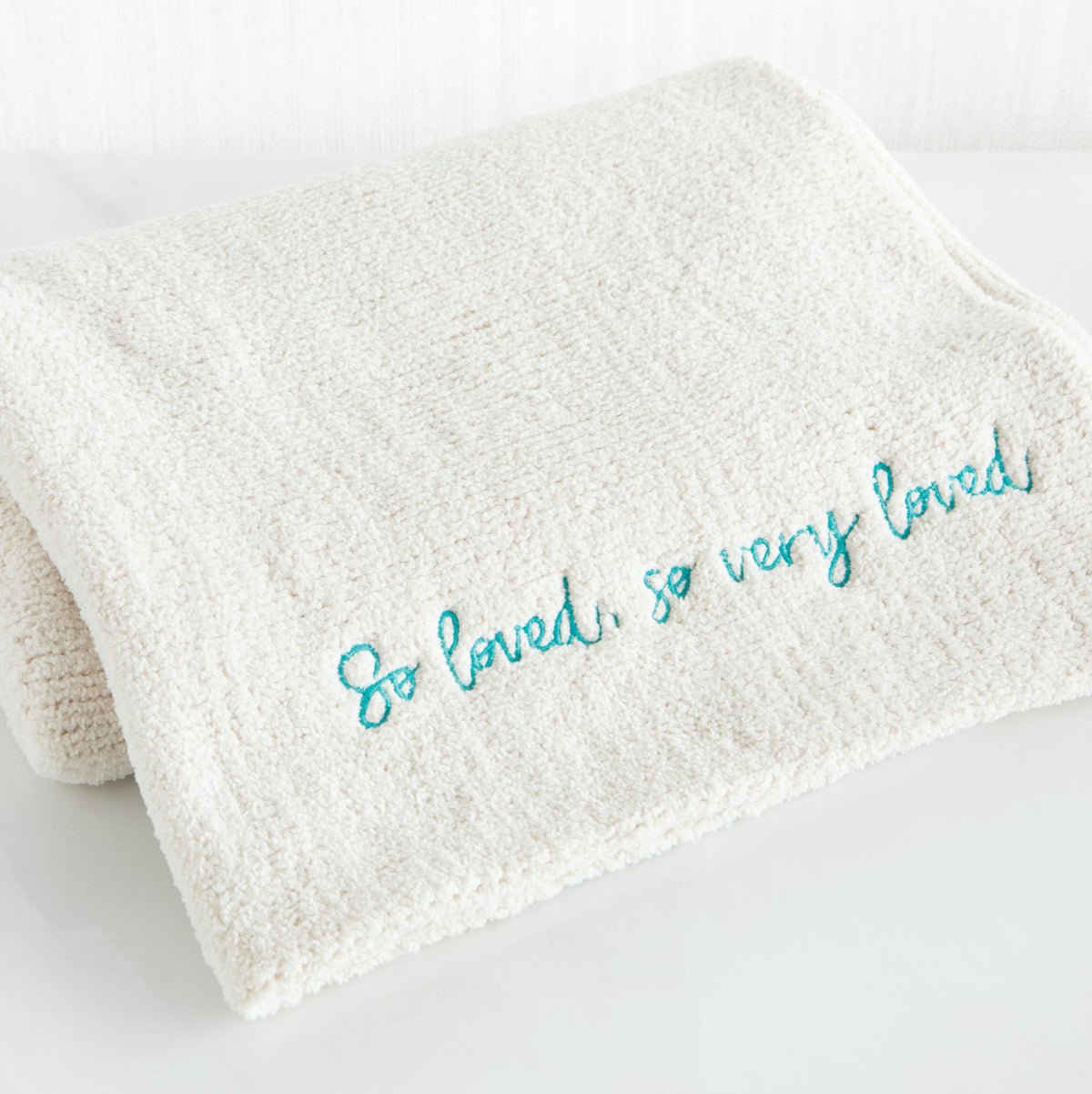Close view of white towel with 'so loved, so very loved' in light blue