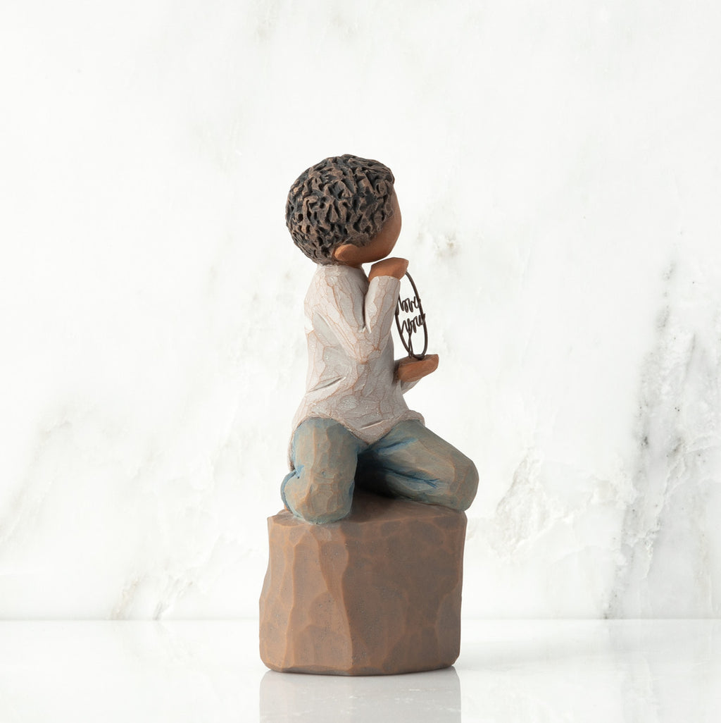 Left view: Figure of darker-skin child, kneeling on rock, holding wire circle with ‘love you’ written in wire