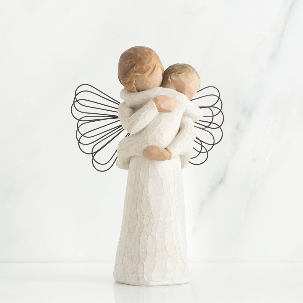 Young girl angel faceless figurine wearing white dress and has black wire wings, holding faceless baby in her arms