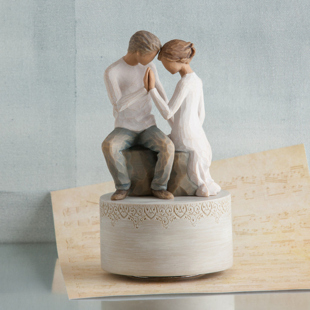 Man and woman figurines holding hands on cream raised rock pendant