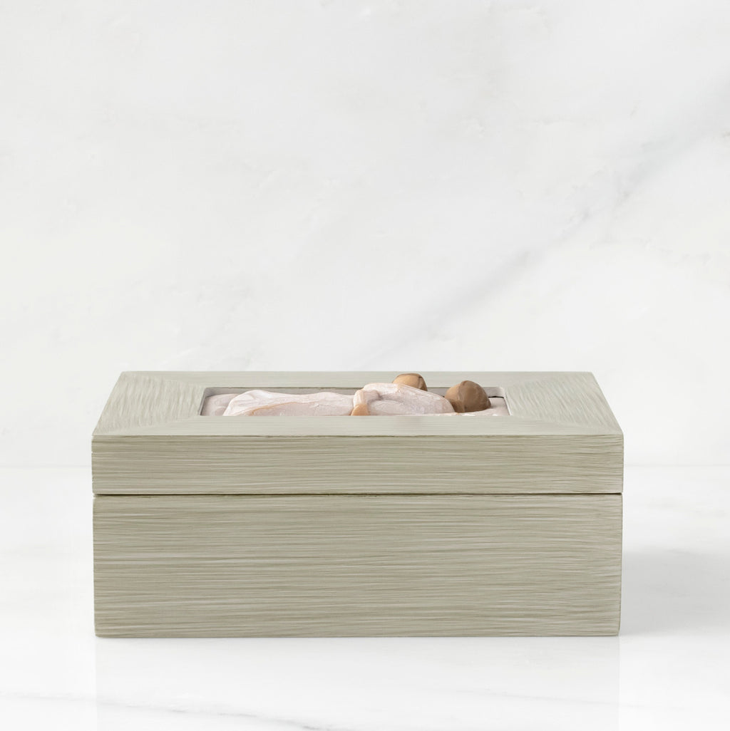 Side view: Light gray rectangular wood box with hinged lid, carving on lid of female and child embracing in cream dresses