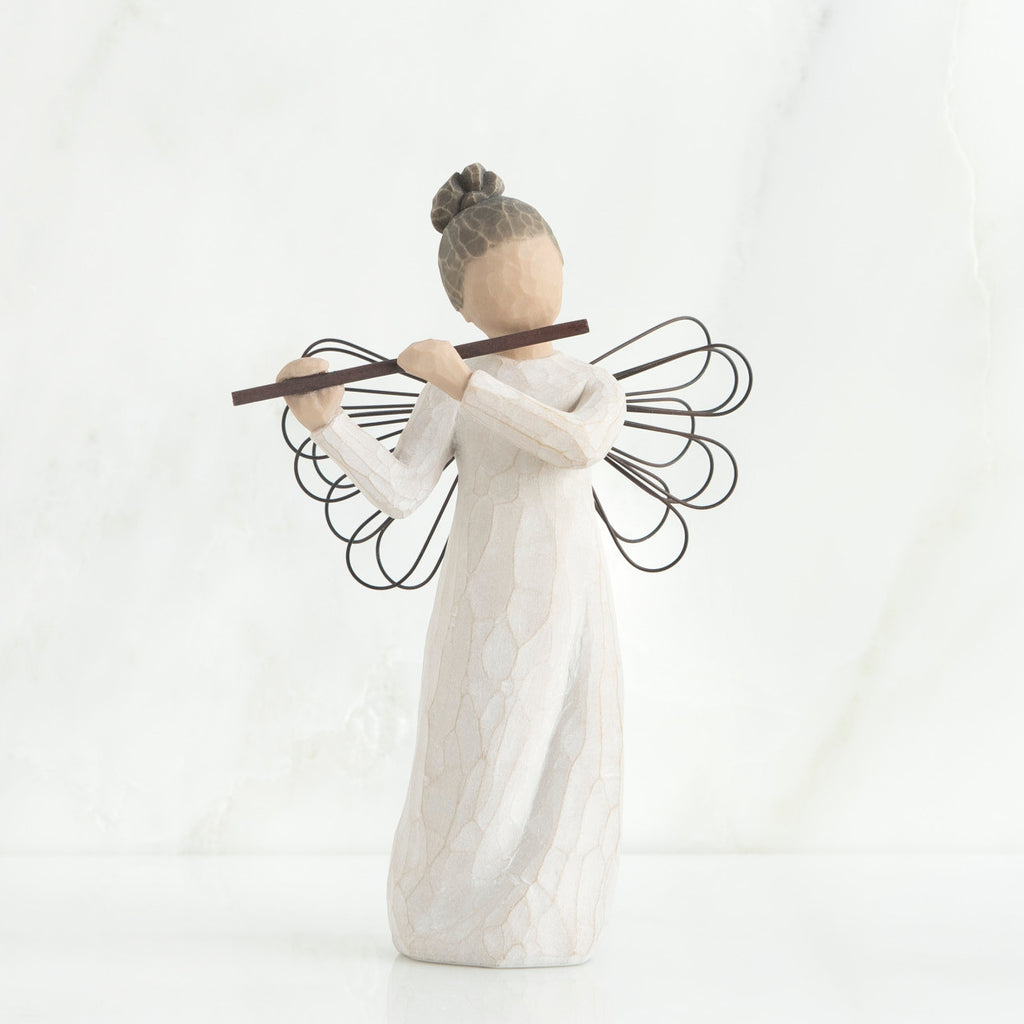 Faceless angel figurine wearing white dress and black wire wings playing black flute