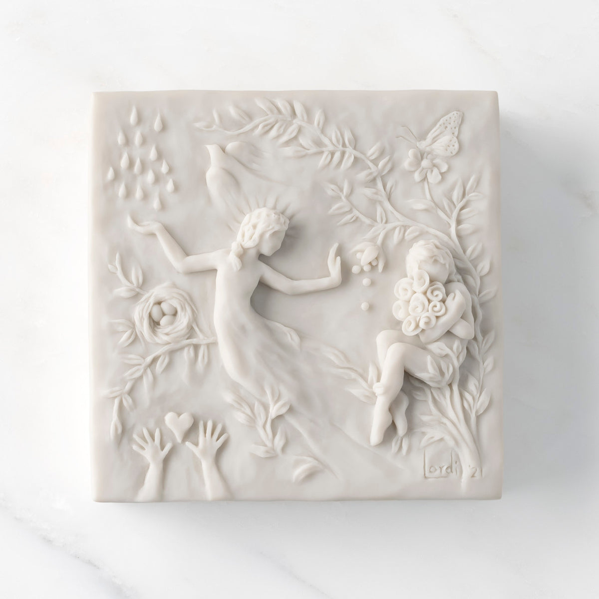 Close-up of white resin box; lid carved with figural and organic imagery