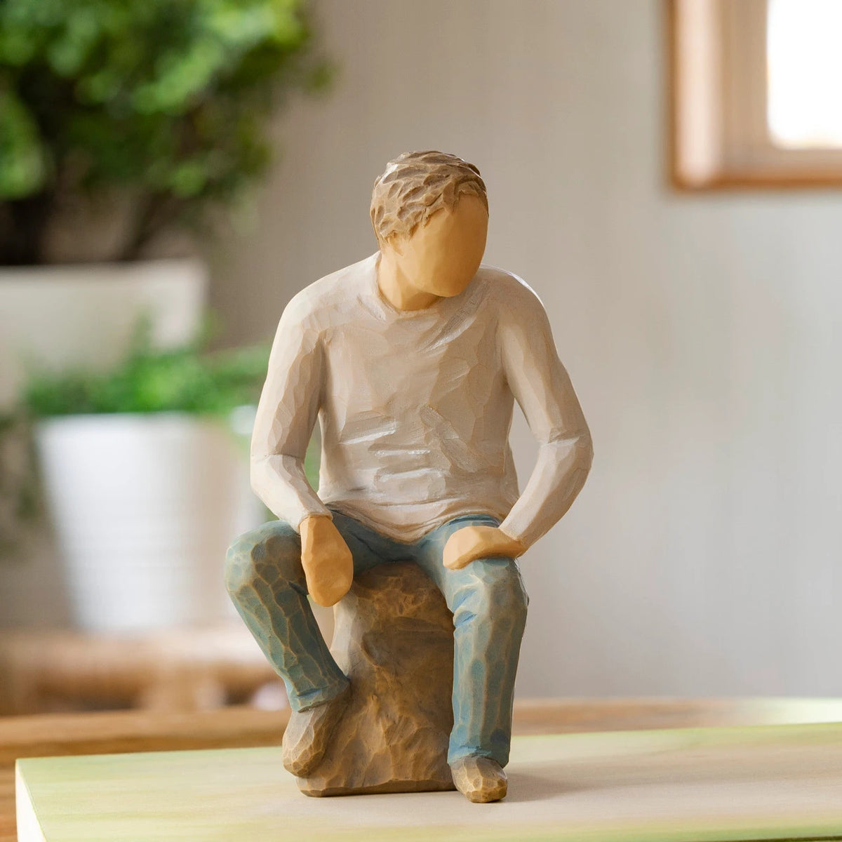 Willow Tree My Guy, 6”h hand-painted resin adult figure in light gray shirt and jeans, seated on gray rock, on wooden table